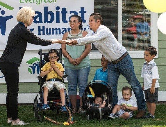 Carol Aaron presents a document to a family at a Habitat for Humanity event
