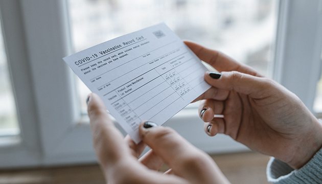 Hands of a young woman hold a COVID-19 vaccination card