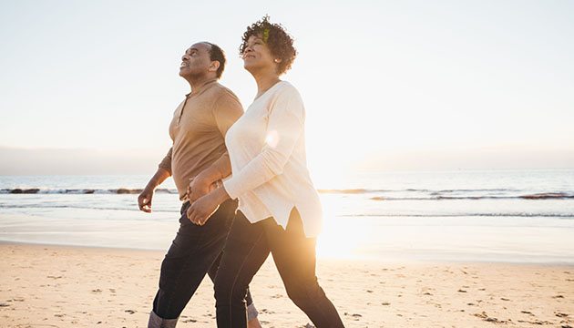 Black man and woman walk on the beach