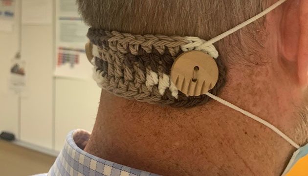 the back of a person wearing a crocheted ear saver and mask