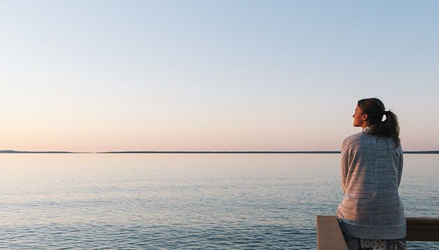 lady sitting on pier by water