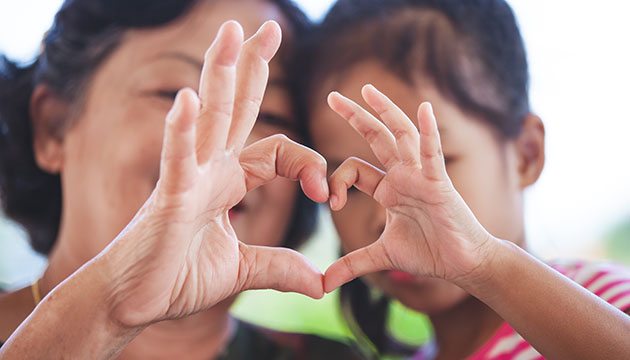 Grandmother and grandchild use hands to form heart