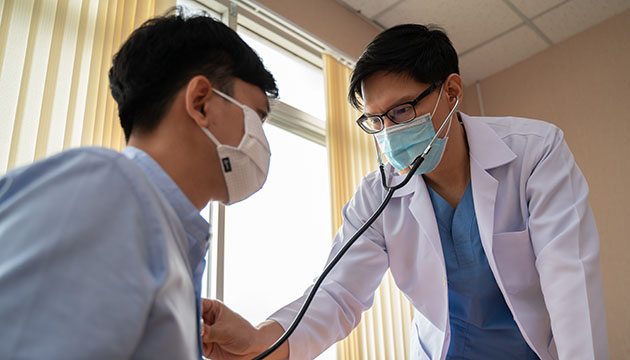 Doctor uses stethoscope to listen to heart of a patient