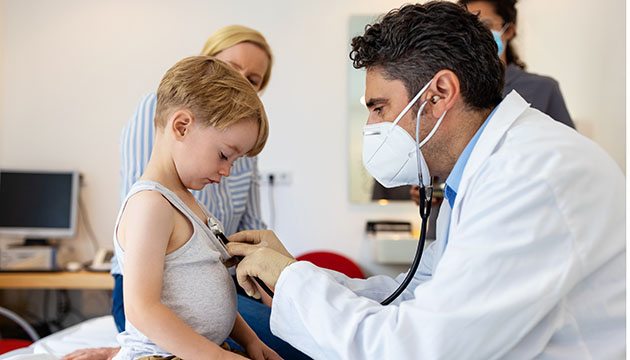 Pediatrician uses stethoscope to listen to little child's heart