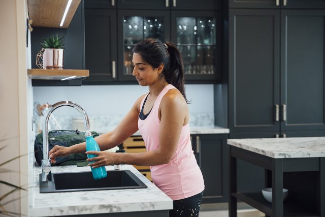 Woman filling water bottle.