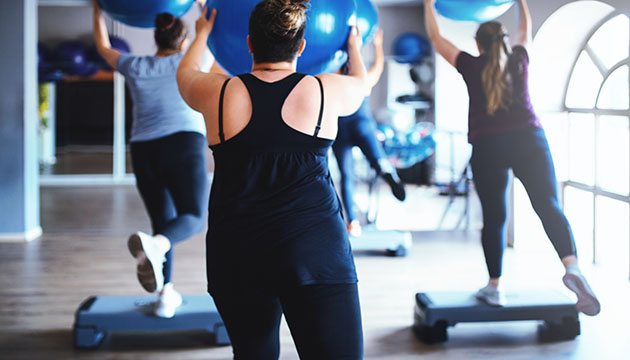 People exercising in class with steps and large rubber balls