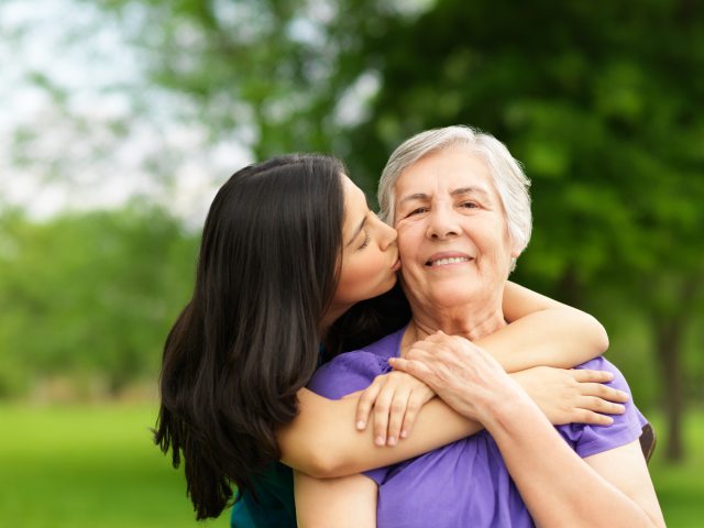 Young woman hugs an older woman from behind