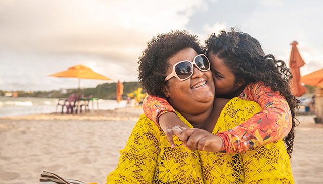 Daughter kisses mom's cheek at beach