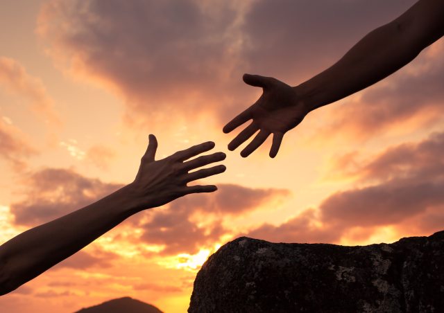 one person's hand reaching out to the hand of another person