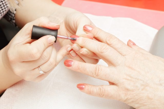 Close-up of two sets of hands, one painting the nails of the other