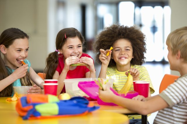 Group of toddlers eat lunch, smile and laugh
