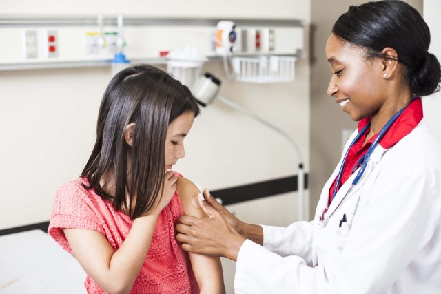 A health care provider administers a vaccine to a young girl