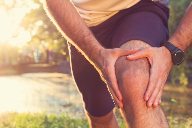 Close-up of a runner holding kne while in pain