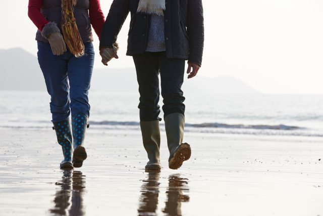 A couple holding hands and walking on the beach