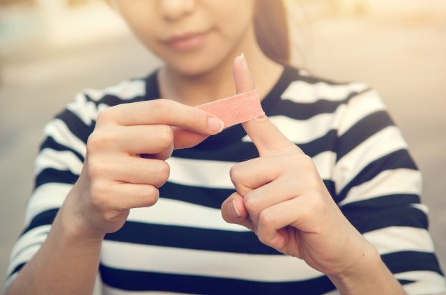 A woman puts a bandage on her left index finger