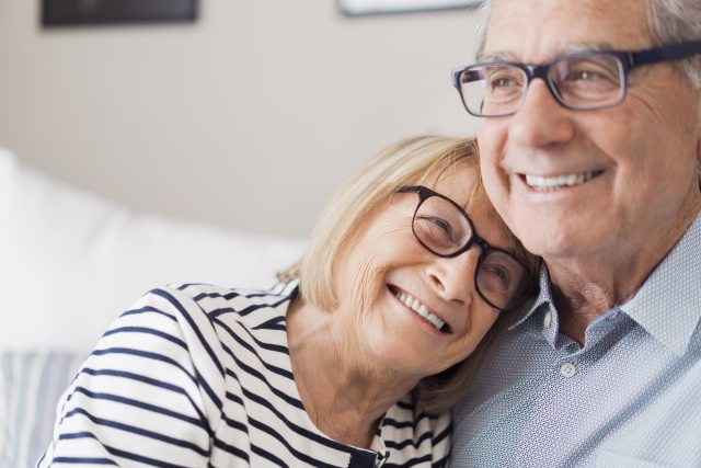 A woman rests her head on a man's shoulder, both are smiling.