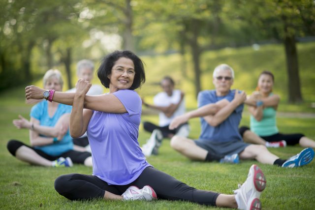 A group of seniors performing stretching exercises in the park