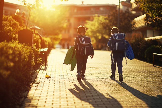Two young boys with backpacks on with sunset in the background