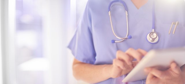 A provider holding a patient chart or ipad