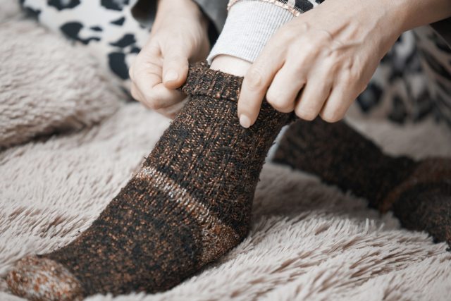 Close-up of hands puling wool socks up over feet and ankle