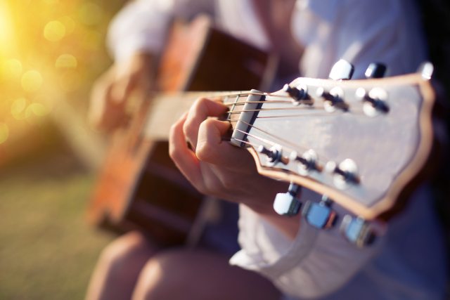 A person playing a C chord on an acoustic guitar