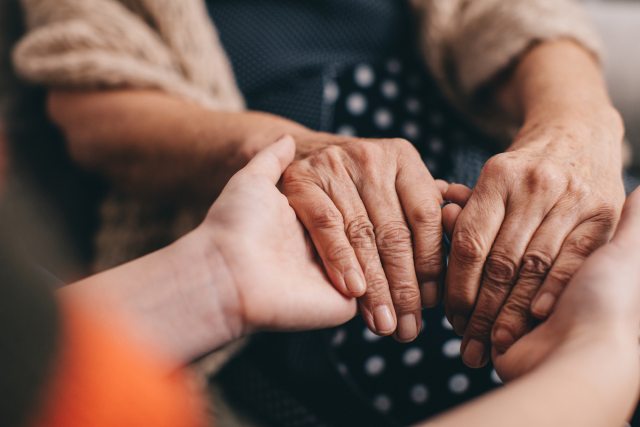 Hands of an older and younger person clasping