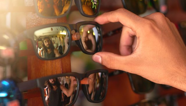 A person chooses sunglasses from a rack