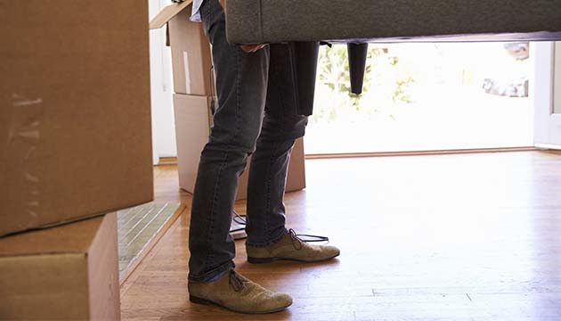 Close-up of  the legs of a person lifting a couch