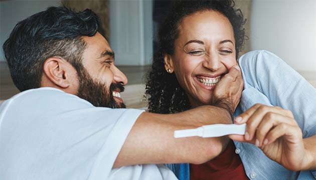A couple smiles while looking at results on an instant pregnancy test