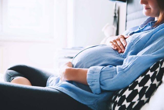 Pregnant woman holds her belly and smiles