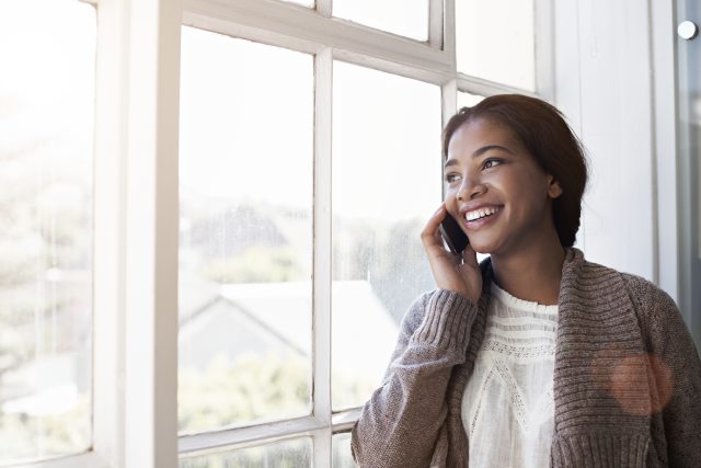 Smiling woman talks on a mobile phone and looks out a window