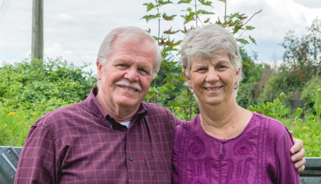 An older couple in matching colored outfits smiles for the camera