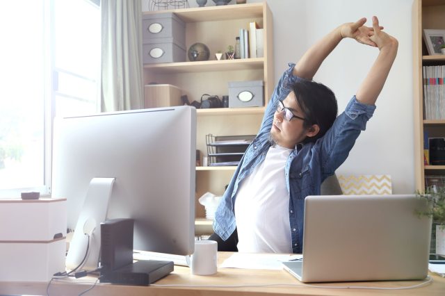 A man stretching at his work desk