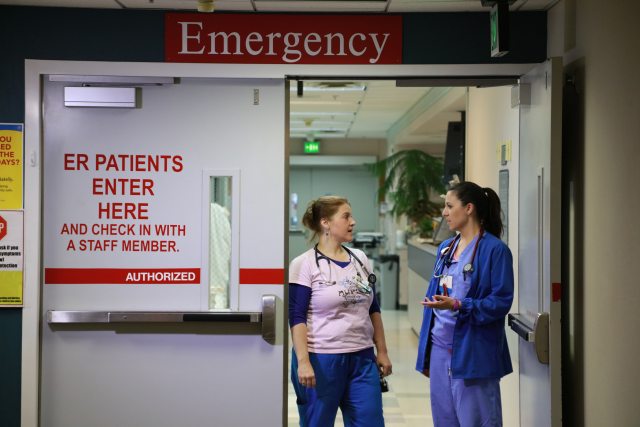 Two nurses chat at the emergency room door entrance