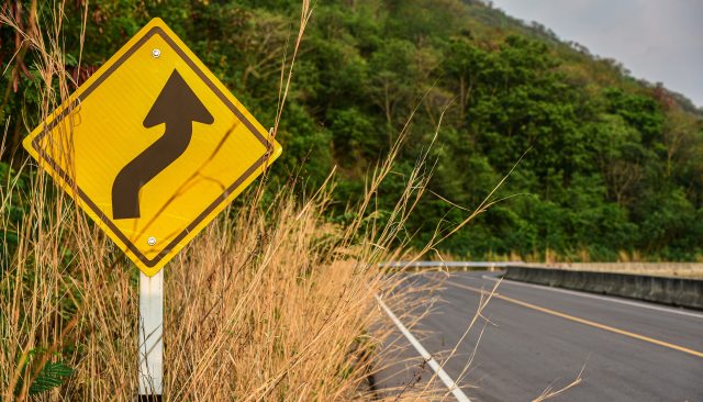 Roadside sign showing curves ahead