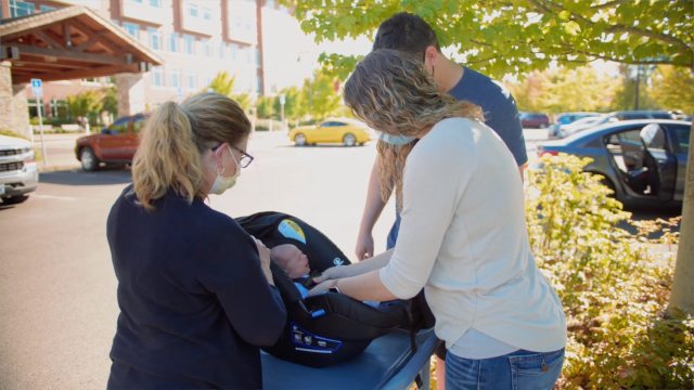 A certified child passenger safety technician instructs parents how to properly buckle their newborn into her car seat before the family leaves PeaceHealth Sacred Heart Medical Center at RiverBend in Springfield, Ore.