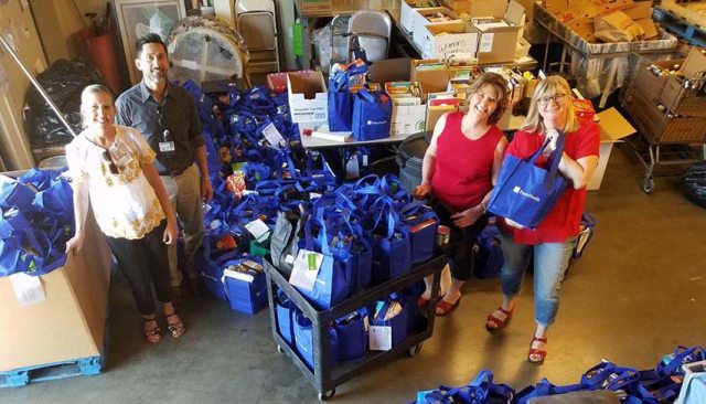 A group of volunteers stop filling donation bags to smile for the camera