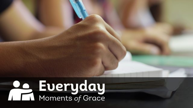 Text of "Everyday Moments of Grace" overlaid on close-up of hand and pen