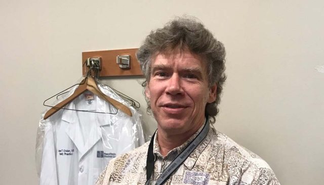 Candid photo of Timothy Randall with doctor's jacket hanging in the background